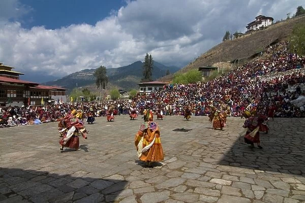 Costumed dancers at religious festival with many visitors, Paro Tsechu