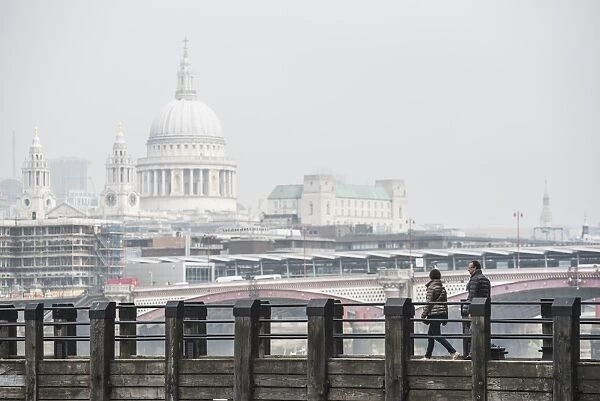 Couple on a pier overlooking St. Pauls Cathedral on the banks of the River Thames