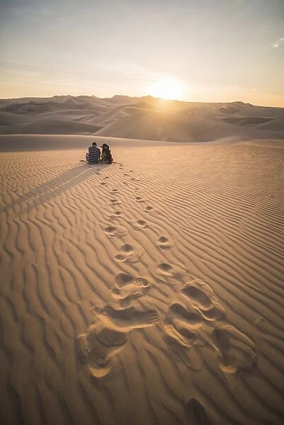Couple watching the sunset over sand dunes in the desert at Huacachina, Ica Region