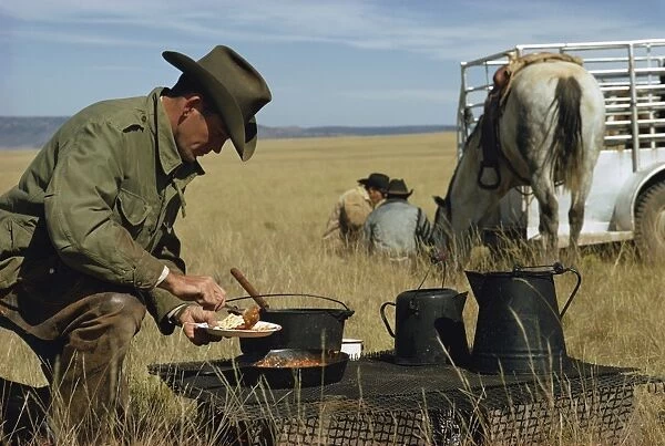 Cowboys eating breakfast in a field