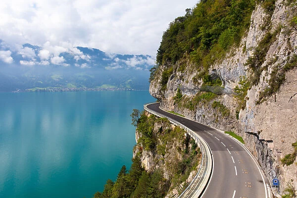 A curved road built into the side of a mountain next to Lake Thun, Interlaken, Bernese Oberland