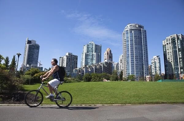 Cyclist passing apartment blocks, False Creek, Vancouver, British Columbia