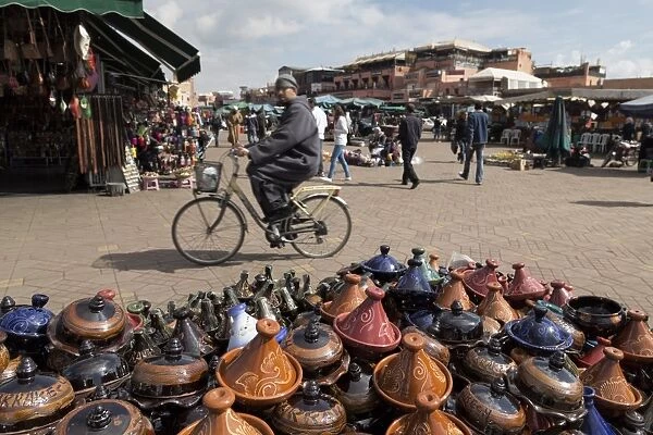 Cyclist passing a stall selling traditional clay tajine cooking pots in Place Jemaa el-Fna, Marrakesh, Morocco, North Africa, Africa