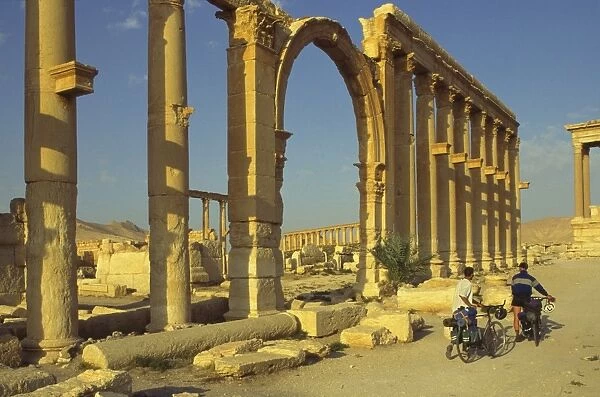 Two cyclists pass the Great Colonnade (Cardo)