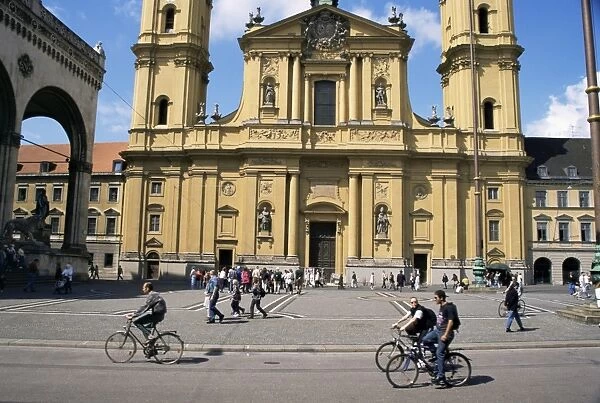 Cyclists passing the Theatinerkirche (church)