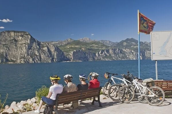 Four cyclists resting by Lake Garda