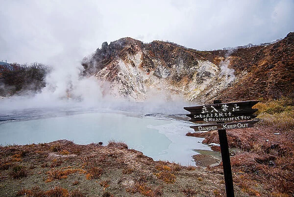 Danger sign in front of volcanic field and steaming pond in Noboribetsu, Hell Valley, Hokkaido, Japan, Asia