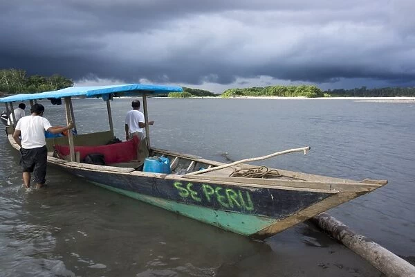 Dark clouds and tourist boat on the Manu river, Manu National Park, UNESCO World Heritage Site, Peru, South America