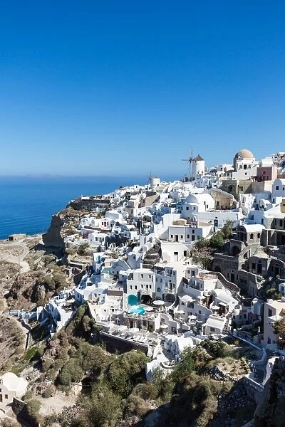 Day time view over the whitewashed buildings and windmill of Oia from the castle walls