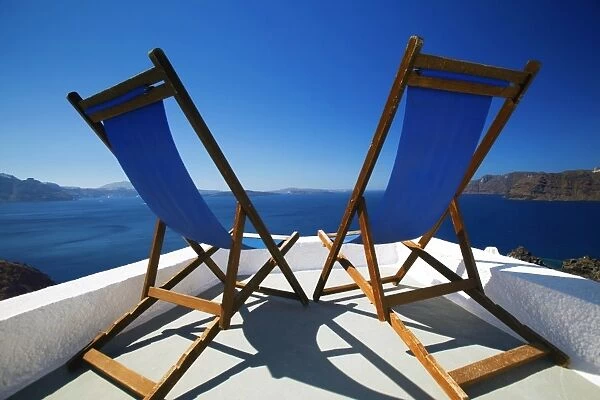 Deck chairs on terrace overlooking ocean, Santorini, Cyclades, Greek Islands, Greece, Europe