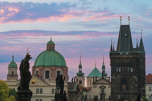 Details of statues and spires at Charles Bridge at sunrise, featuring dome of Church of Saint Francis of Assisi and Old Town Bridge Tower, UNESCO World Heritage Site Prague, Bohemia, Czech Republic (Czechia), Europe