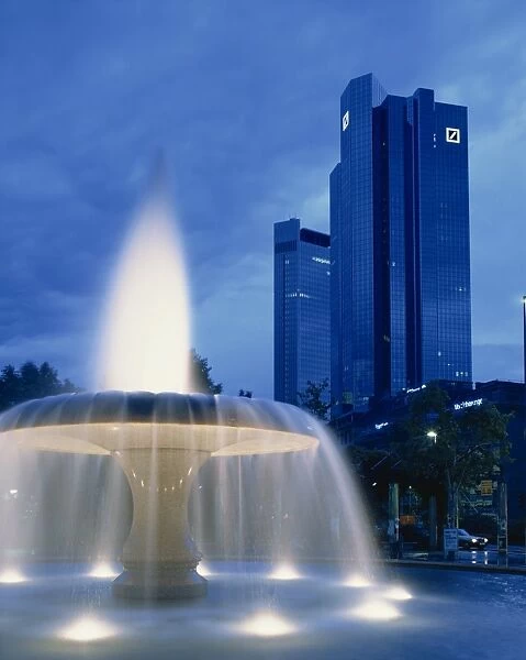 The Deutsche Bank with water fountain illuminated at dusk