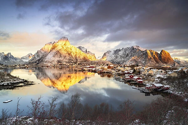 Dramatic sky at dawn over Mount Olstind covered with snow, Reine Bay, Nordland