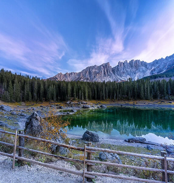 Dramatic sky at sunset over Carezza Lake and Latemar peaks in autumn, Dolomites
