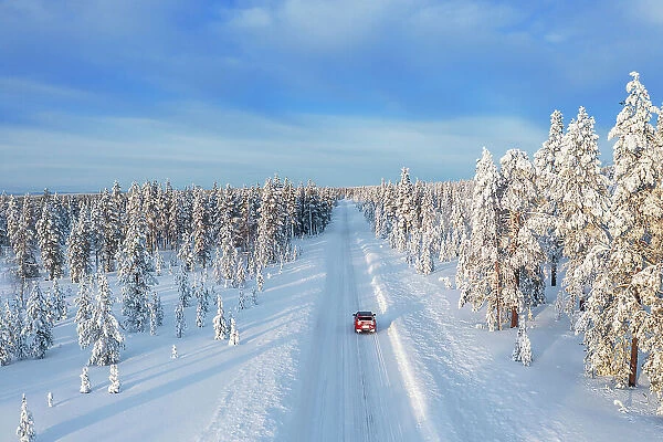 Drone view of a car driving on an empty and frozen road in the white landscape of Swedish Lapland, Sweden, Scandinavia, Europe