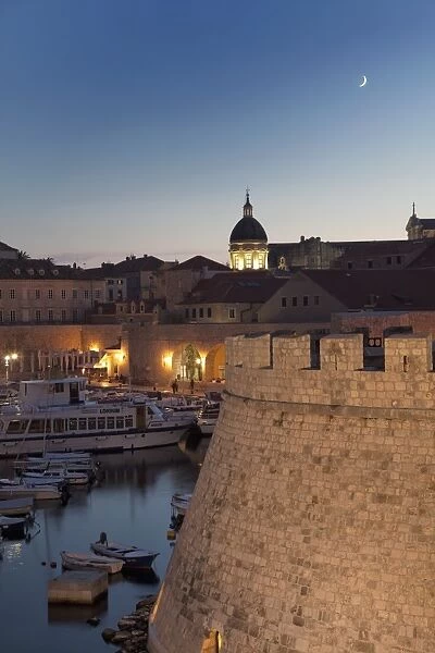 Dubrovnik Old Town port with the dome of the Cathedral illuminated at dusk, UNESCO World Heritage Site, Dubrovnik, Croatia, Europe
