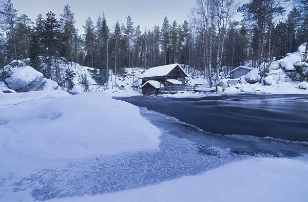Dusk frames the frozen water in the snowy woods and a wooden hut, Juuma, Myllykoski