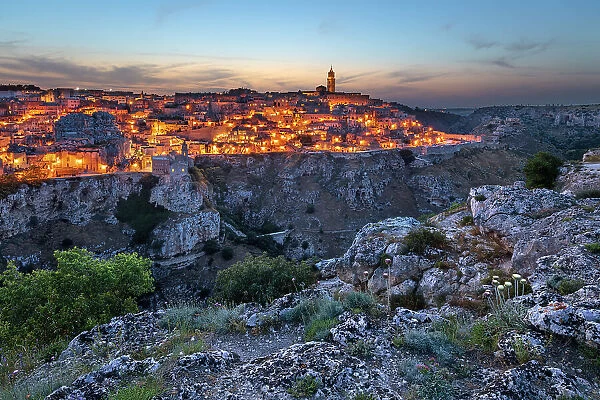 Dusk over the Gravina River canyon and the floodlit Sassi di Matera old town, UNESCO World Heritage Site, Matera, Basilicata, Italy, Europe