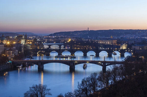 Dusk lights up the historical bridges and buildings reflected on Vltava River, Prague