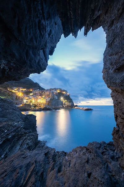 Dusk lights over Manarola seen from a sea cave, Cinque Terre, UNESCO World Heritage Site