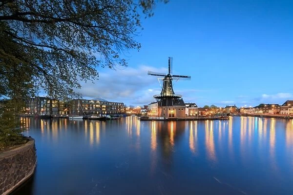 Dusk lights on the Windmill De Adriaan reflected in the River Spaarne, Haarlem, North Holland
