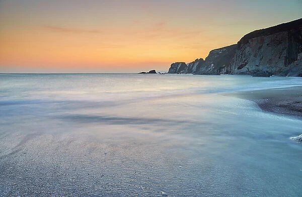 A dusk view of surf surging ashore at Ayrmer Cove, a remote cove near Kingsbridge, south coast of Devon, England, United Kingdom, Europe