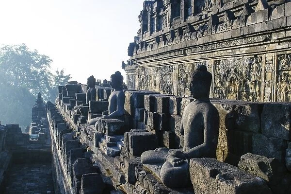 Early morning light shining on Buddhas sitting in the temple complex of Borobodur, UNESCO World Heritage Site, Java, Indonesia, Southeast Asia, Asia