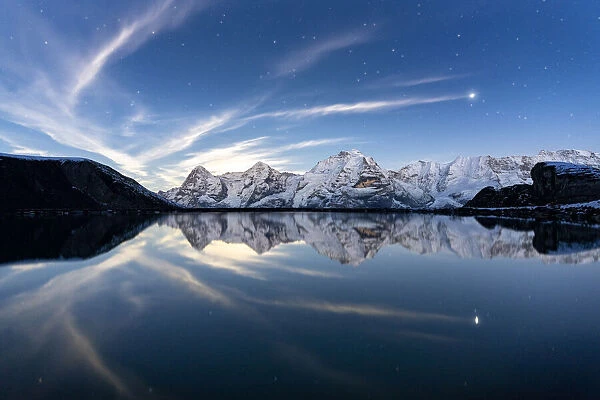 Eiger, Monch and Jungfrau mountains mirrored in Engital lake under the stars, Murren Birg