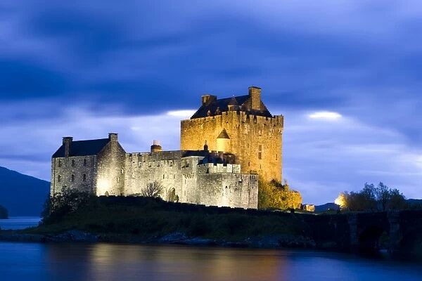 Eilean Donan Castle floodlit against deep blue twilight sky and water of Loch Duich