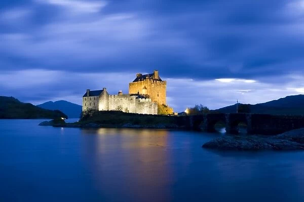 Eilean Donan Castle floodlit against the deep blue twilight sky and water of Loch Duich
