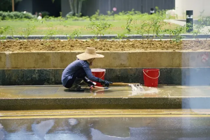 Framed Print : An elderly woman in a straw hat washes the pavement Framed Print : An elderly woman in a straw hat washes the pavement