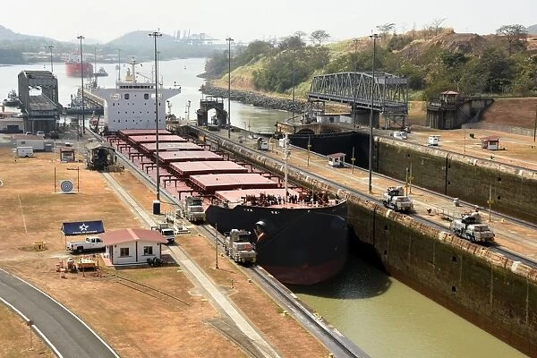 Electric mules guiding Panamax ship through Miraflores Locks on the Panama Canal