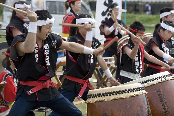 Energetic group of drummers beating Japanese taiko drums during an outdoor performance