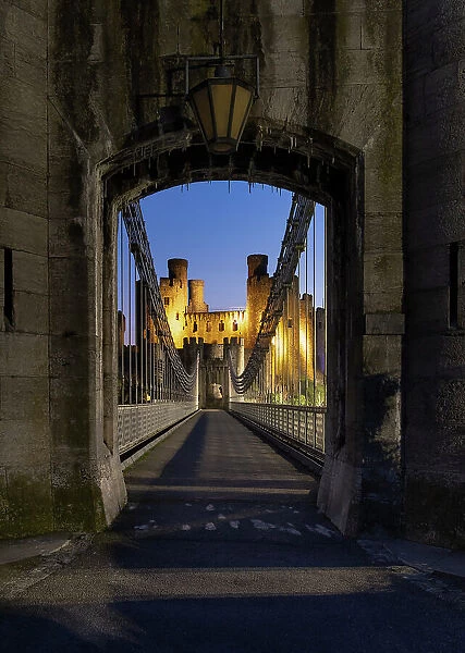 Entrance to Telford's Conwy Suspension Bridge and Conwy Castle at night, UNESCO World Heritage Site, Conwy, North Wales, United Kingdom, Europe