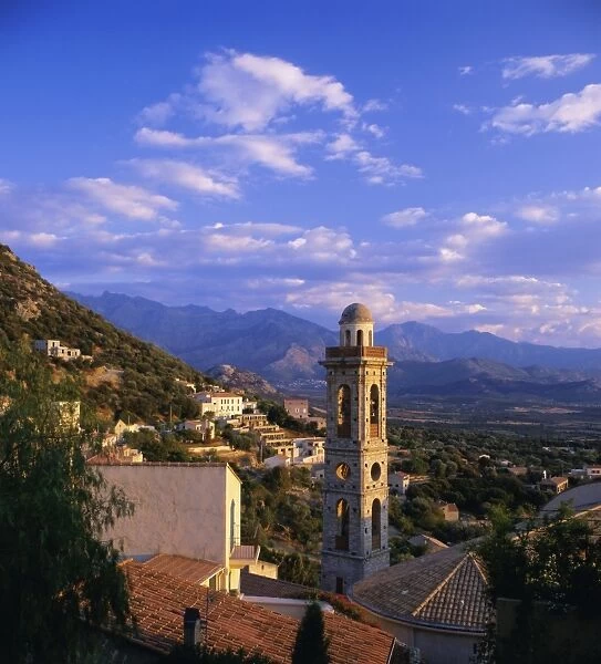 Evening view across rooftops and church tower to mountains, Lumio, near Calvi