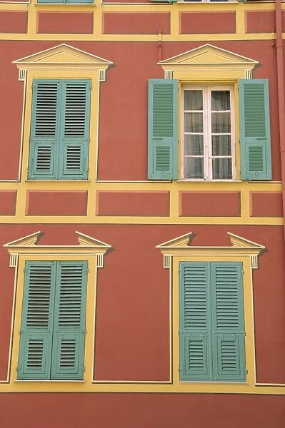 Exterior of a formal facade, brightly painted, with blue shutters and orange walls