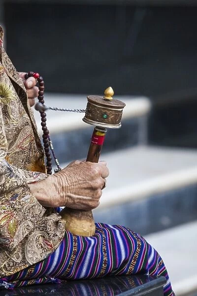 A faithful Buddhist uses the traditional portable roller-book (prayer wheel), Bhutan