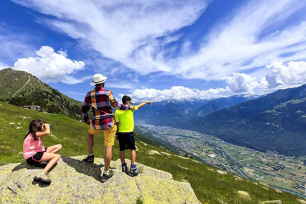 Father and children enjoy the view towards Morbegno from Alpe Bassetta, Lower Valtellina