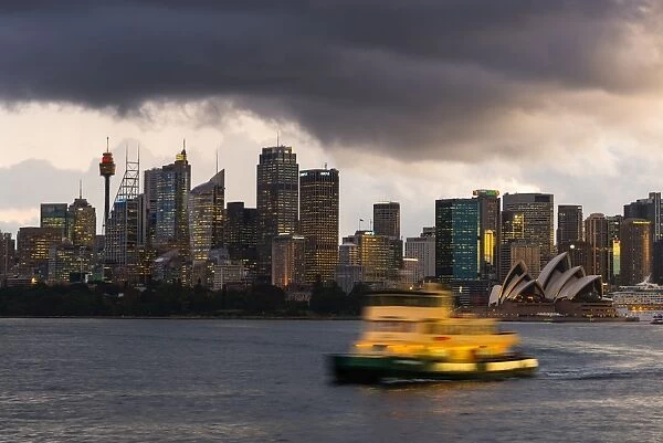 A ferry in Sydney Harbour at dusk with the Opera House and city skyline, Sydney, New South Wales
