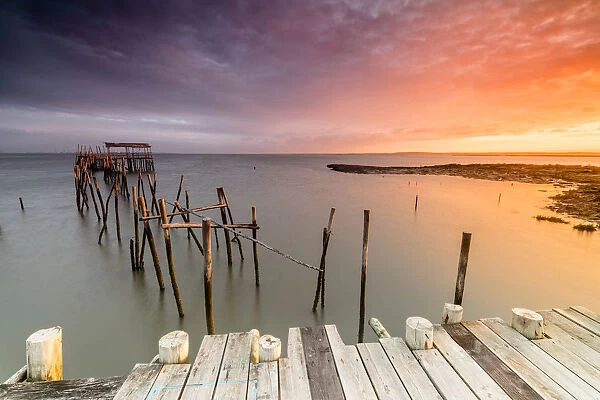 Fiery sky at dawn on the Palafito Pier in the Carrasqueira Natural Reserve of Sado River