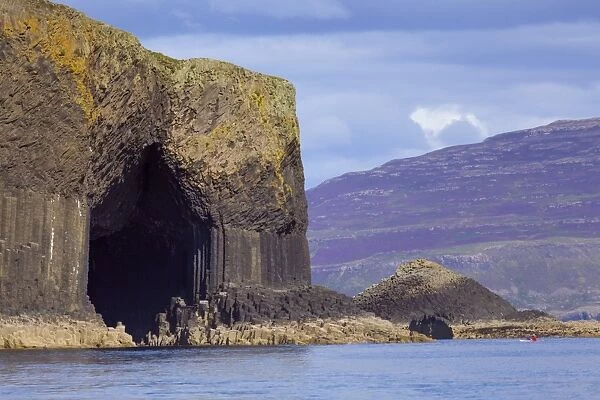 Fingals Cave, the hexagonal mouth of the cave with the heather-covered slopes of Mull behind, Argyll and Bute, Scotland, United Kingdom, Europe