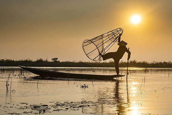 Fisherman at Inle Lake with traditional Intha conical net at sunset, fishing net