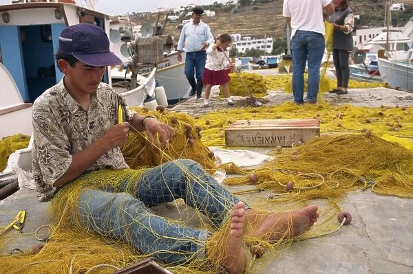 Fisherman using hands and feet to repair fishing net on Mykonos