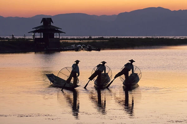 Three fishermen balance on one leg at sunset on Inle Lake, Shan State, Myanmar (Burma)