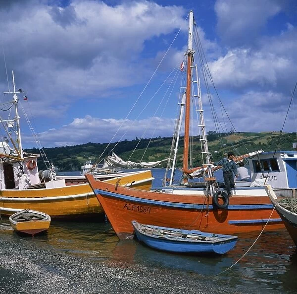Fishermen on fishing boats moored on the beach at Dalcahue village on Chiloe Island