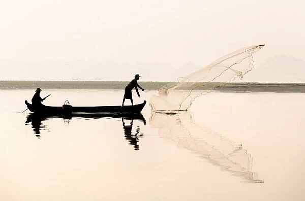 Fishermen on Taungthaman Lake in dawn mist, casting net near U Bein Bridge, Amarapura, near Mandalay, Myanmar (Burma), Asia