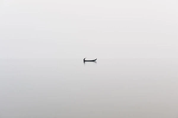 A fishing boat on a perfectly calm Indawgyi Lake in northern Myanmar on a misty afternoon