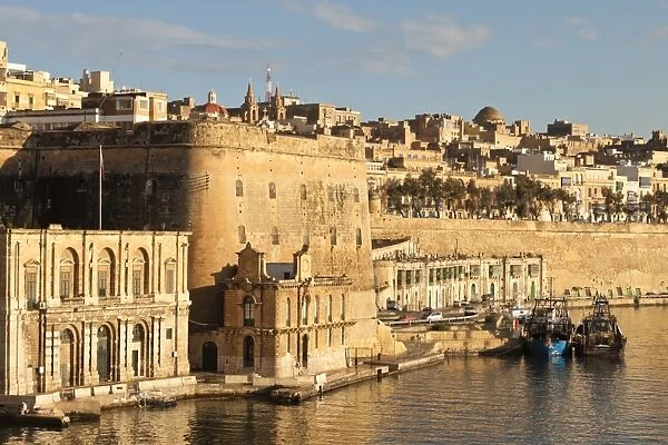 Fishing boats at the Barriera Wharf and Grand Harbour fortifications in the golden early morning, Valletta, Malta, Mediterranean, Europe