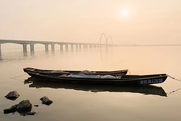 Fishing boats and modern bridge in mist at Qiantangjiang River in Hangzhou, Zhejiang, China, Asia