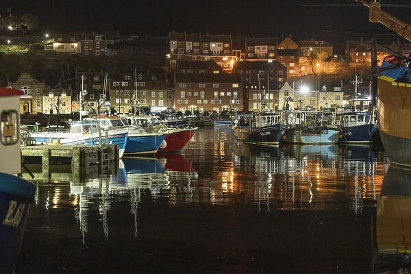 Fishing boats moored in Whitby harbour at night, Whitby, North Yorkshire, England